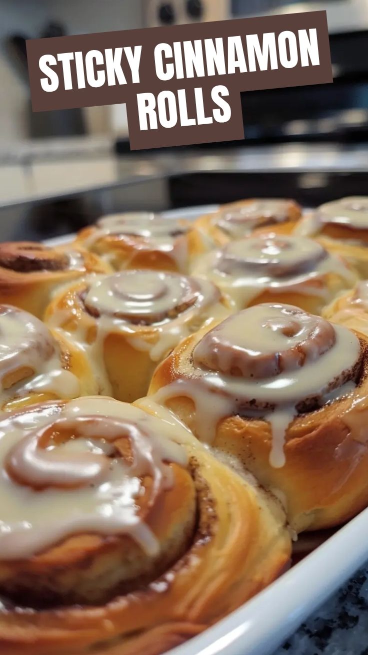 Freshly baked homemade cinnamon rolls with icing on a cooling rack.