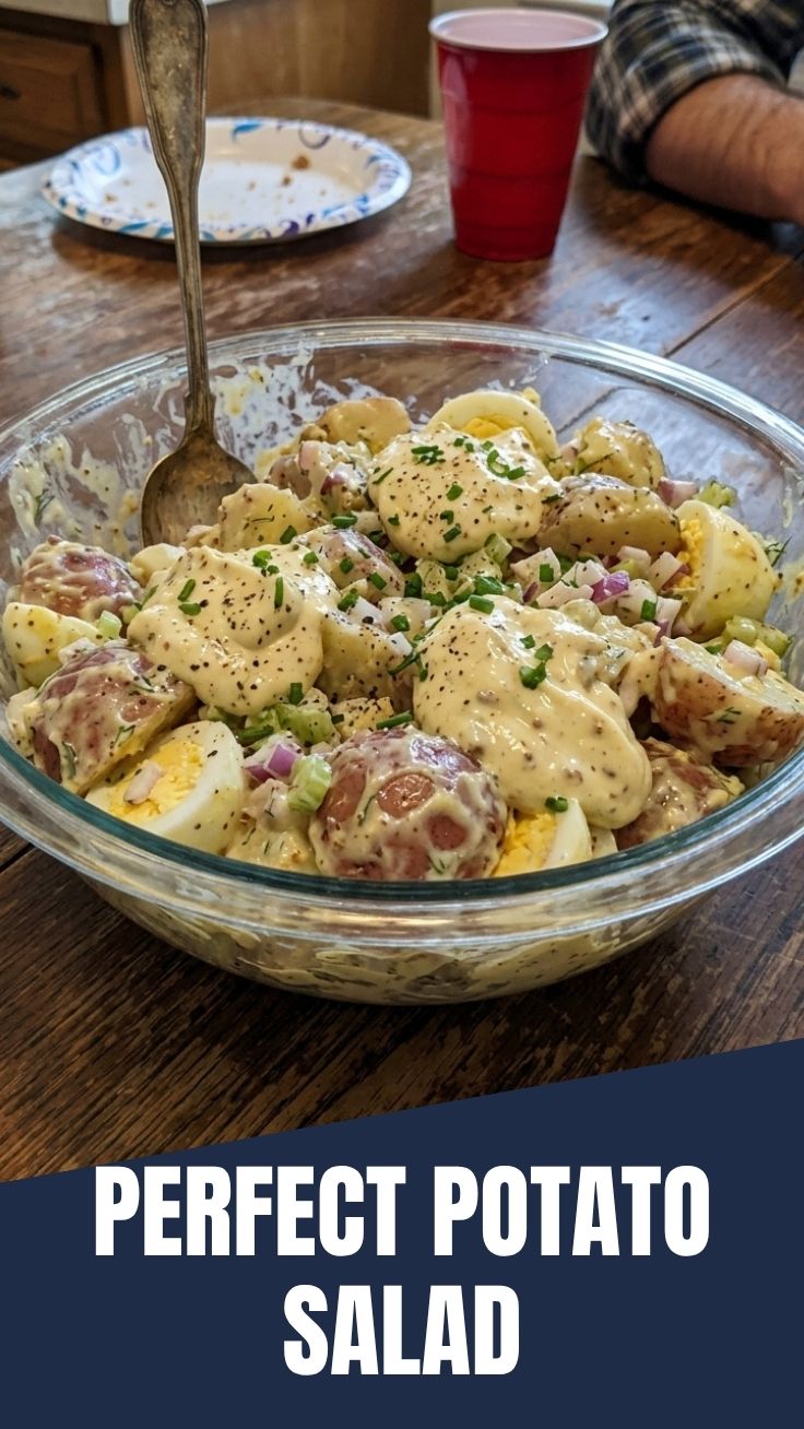 A bowl of creamy potato salad garnished with fresh herbs