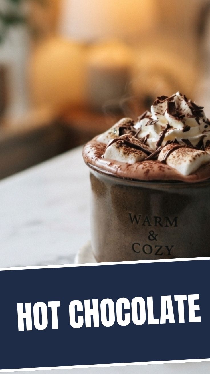 A steaming mug of hot chocolate topped with whipped cream and chocolate shavings